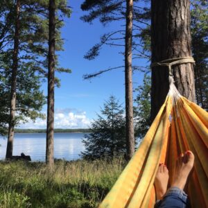 Henkilö makaa kesäisessä masemassa riippumatossa