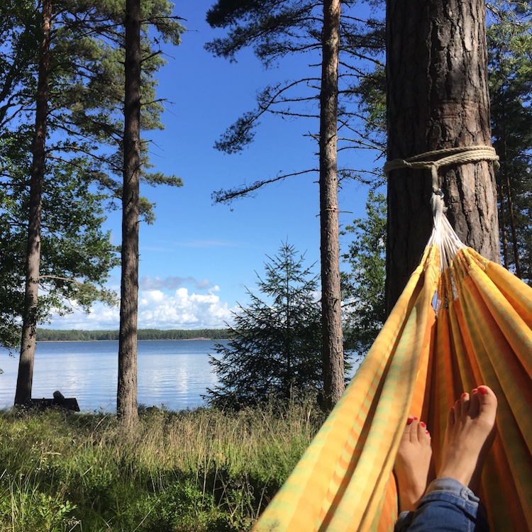 Henkilö makaa kesäisessä masemassa riippumatossa